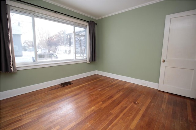 empty room with hardwood / wood-style flooring, a wealth of natural light, and crown molding