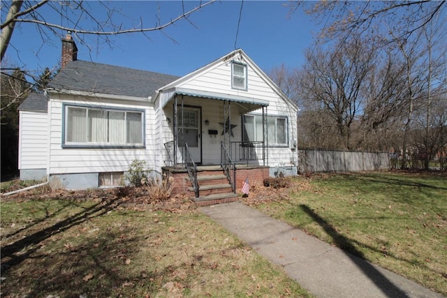 bungalow-style home with a chimney, covered porch, a front yard, and fence