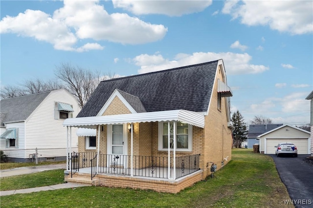 view of front of home featuring a garage, covered porch, an outbuilding, and a front lawn