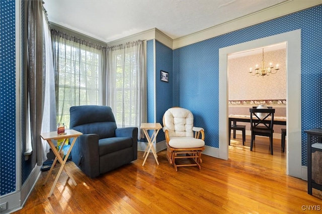 living area featuring crown molding, wood-type flooring, and an inviting chandelier