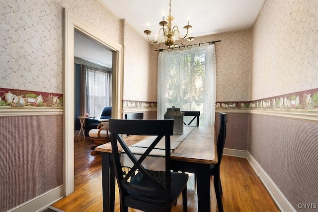 dining space featuring crown molding, a notable chandelier, and hardwood / wood-style flooring