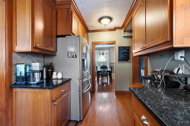 kitchen featuring tasteful backsplash, stainless steel fridge with ice dispenser, dark stone counters, and light wood-type flooring