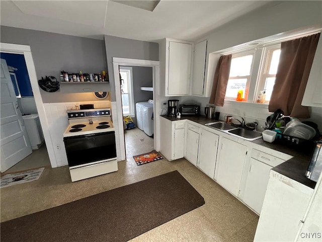 kitchen featuring electric range, washing machine and dryer, white cabinetry, and sink