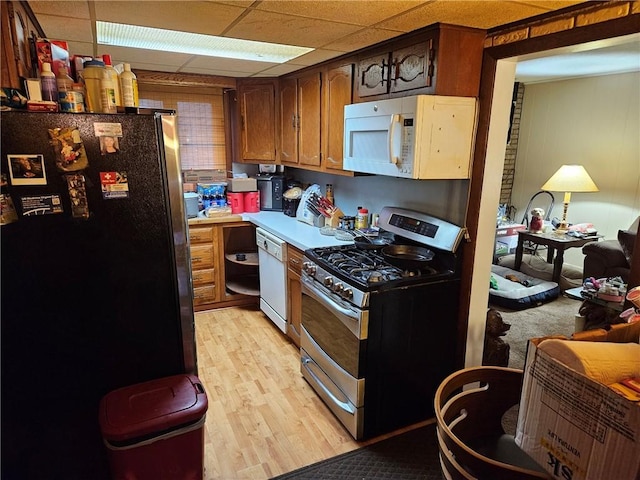 kitchen featuring a paneled ceiling, light hardwood / wood-style flooring, and white appliances