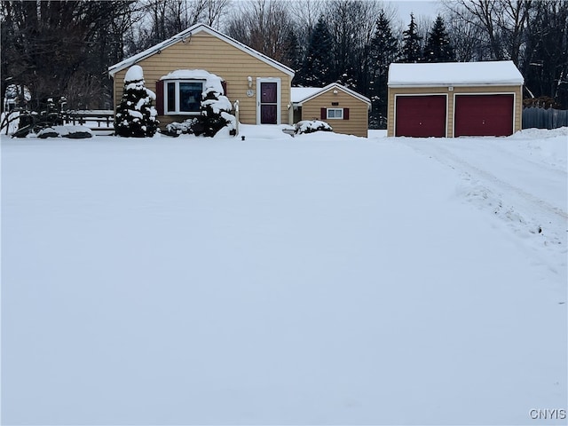 yard covered in snow featuring an outbuilding and a garage