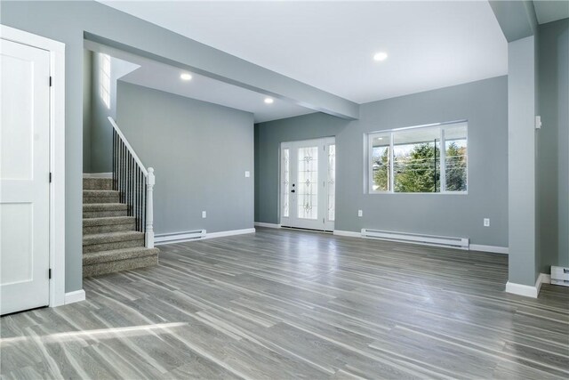 unfurnished living room featuring baseboard heating and hardwood / wood-style floors