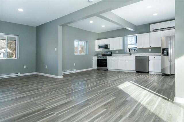 kitchen featuring an AC wall unit, white cabinetry, a baseboard heating unit, and appliances with stainless steel finishes