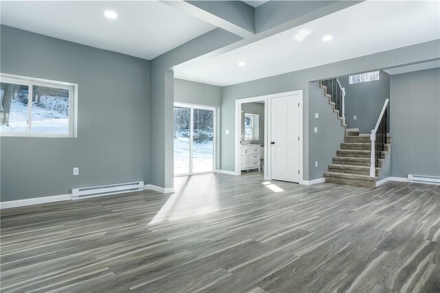 unfurnished living room featuring dark wood-type flooring and a baseboard heating unit