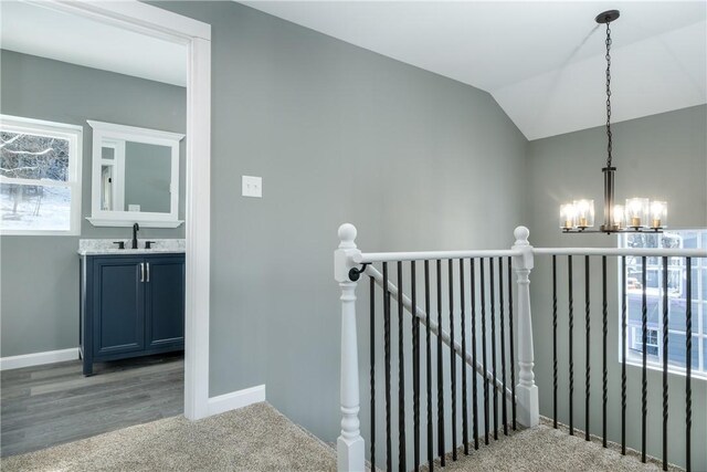 stairs with sink, carpet, lofted ceiling, and a notable chandelier