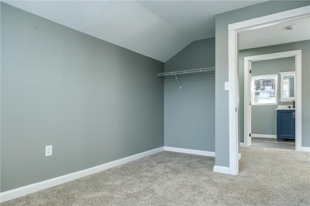 walk in closet featuring light colored carpet and vaulted ceiling