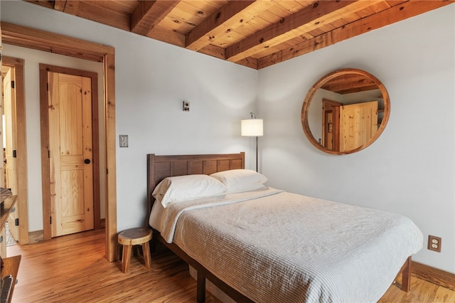 bedroom featuring beamed ceiling, light hardwood / wood-style floors, and wooden ceiling