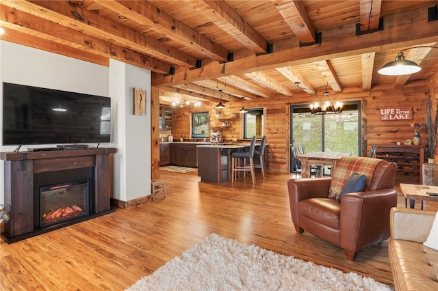 living room with log walls, beamed ceiling, a notable chandelier, light hardwood / wood-style floors, and wood ceiling