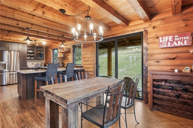 dining space featuring rustic walls, wooden ceiling, a notable chandelier, beamed ceiling, and hardwood / wood-style floors