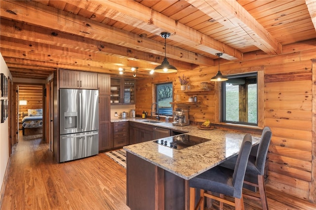 kitchen featuring log walls, hanging light fixtures, beamed ceiling, kitchen peninsula, and appliances with stainless steel finishes