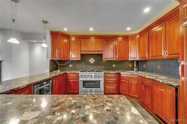 kitchen featuring appliances with stainless steel finishes, hanging light fixtures, sink, dark stone countertops, and kitchen peninsula