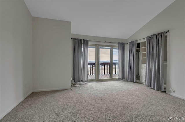 empty room featuring vaulted ceiling and carpet flooring