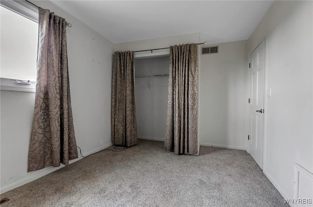 unfurnished bedroom featuring a closet and light colored carpet