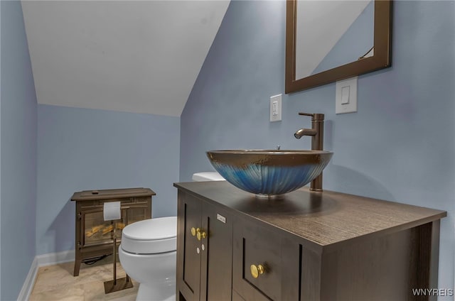 bathroom featuring vanity, vaulted ceiling, and toilet