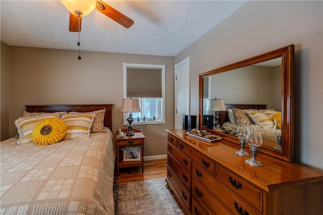 bedroom featuring ceiling fan, light hardwood / wood-style floors, and a textured ceiling