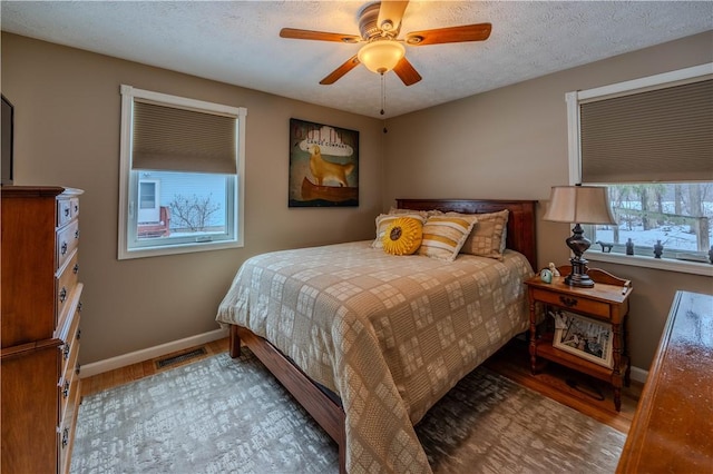 bedroom featuring ceiling fan, light hardwood / wood-style flooring, and a textured ceiling