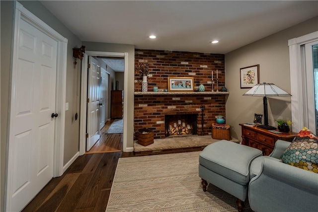 living room with dark hardwood / wood-style flooring and a brick fireplace