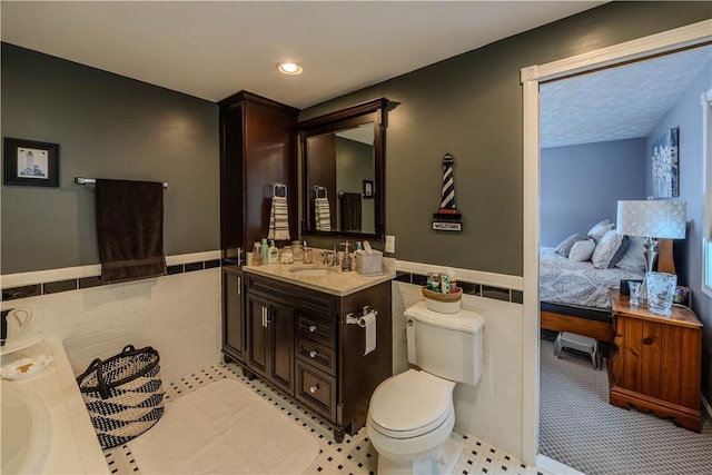 bathroom featuring vanity, tile walls, and toilet