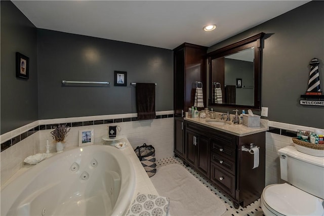 bathroom featuring vanity, toilet, tile walls, and tiled tub