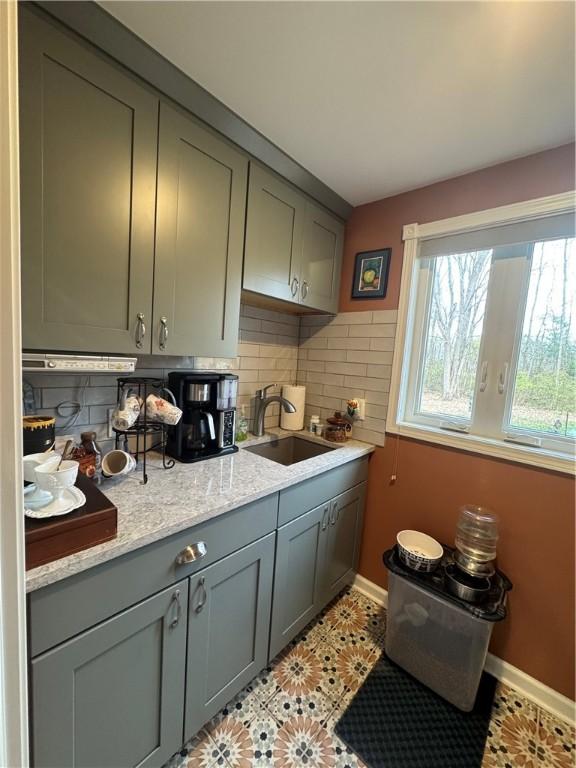 kitchen with sink, light tile patterned floors, backsplash, and light stone counters