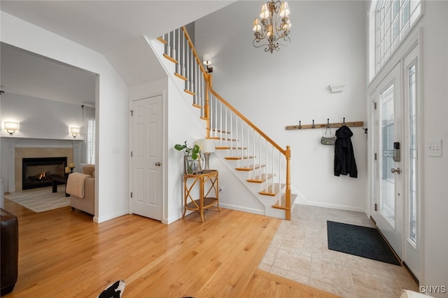 foyer featuring french doors, wood-type flooring, a fireplace, and an inviting chandelier