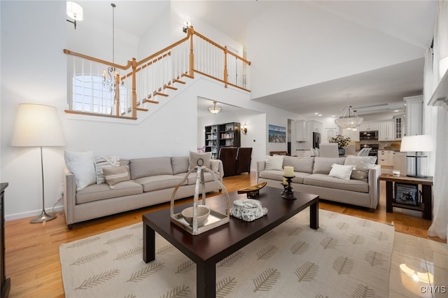 living room with high vaulted ceiling, a notable chandelier, and light wood-type flooring