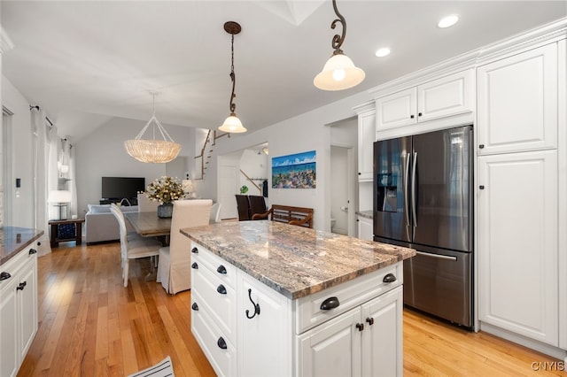 kitchen featuring a center island, dark stone counters, white cabinets, hanging light fixtures, and stainless steel fridge with ice dispenser