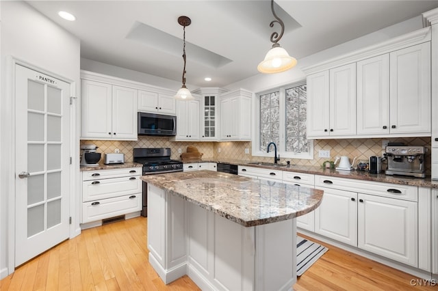 kitchen featuring white cabinets, appliances with stainless steel finishes, and hanging light fixtures