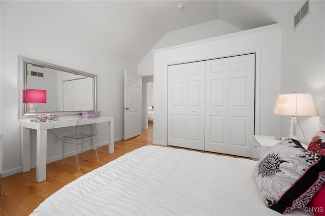 bedroom featuring light hardwood / wood-style floors, lofted ceiling, and a closet