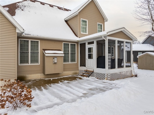 snow covered property featuring a sunroom