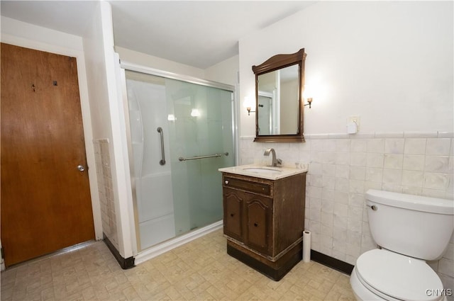 bathroom featuring vanity, a shower with shower door, tile walls, and toilet