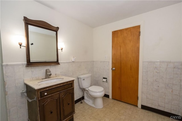 bathroom featuring vanity, toilet, and tile walls