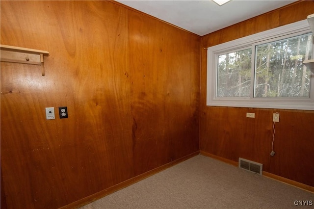 carpeted empty room with wood walls