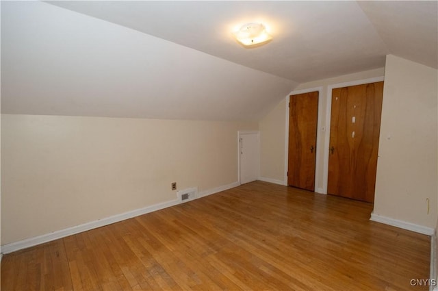 additional living space with hardwood / wood-style floors and lofted ceiling