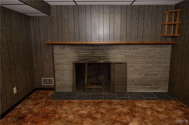 details featuring a stone fireplace, wood walls, carpet floors, and a paneled ceiling