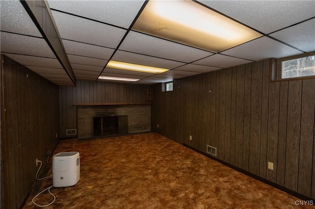 basement featuring dark colored carpet and wooden walls