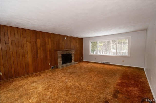 unfurnished living room featuring carpet floors, a stone fireplace, and wooden walls