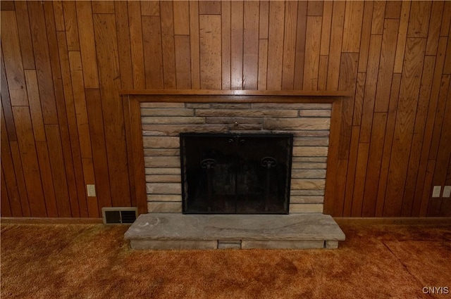 interior details with carpet flooring, wood walls, and a fireplace