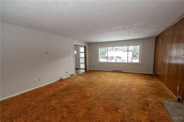 spare room featuring wooden walls and carpet