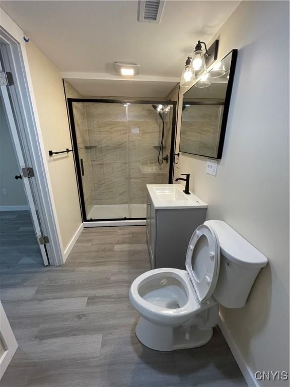 bathroom featuring vanity, hardwood / wood-style flooring, toilet, and an enclosed shower