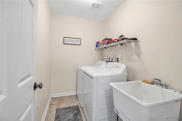 clothes washing area featuring light tile patterned floors, washing machine and dryer, and sink