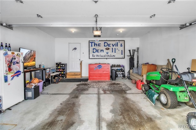 garage featuring white fridge and a garage door opener