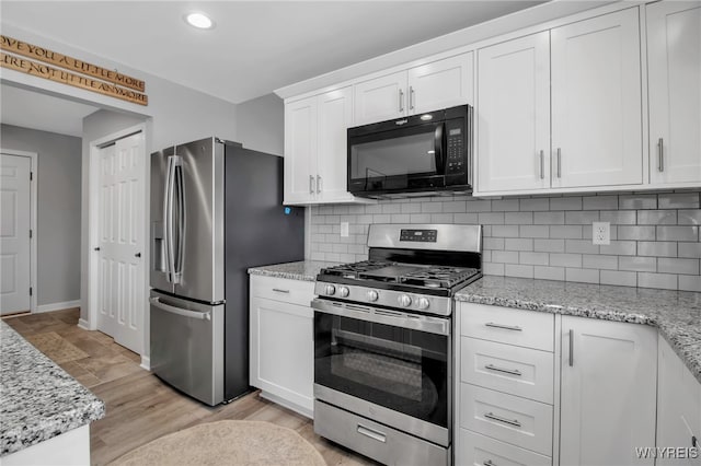 kitchen featuring white cabinets, light stone counters, appliances with stainless steel finishes, and tasteful backsplash