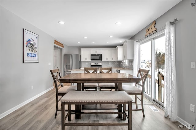 dining space featuring light wood-type flooring and sink