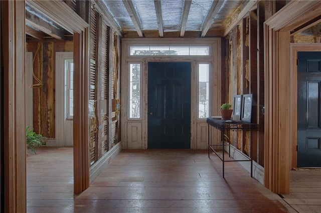 entrance foyer featuring a healthy amount of sunlight, beamed ceiling, and wood-type flooring