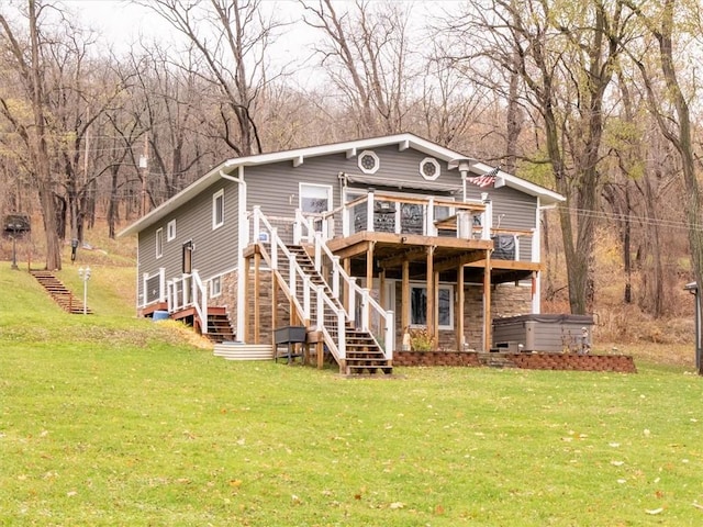 back of house featuring a lawn, a wooden deck, and a hot tub